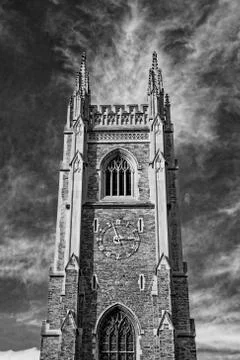 Gothic tower in front of bright blue sky with white cirrus clouds Stock Photos