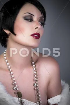 Gourgeos female brunette flapper wearing pearls and fur Stock Photos