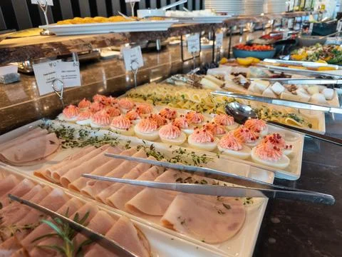 A gourmet breakfast buffet spread with sliced ham and stuffed eggs on white Stock Photos