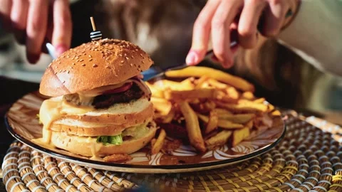 Gourmet burger served on a patterned plate in bright daylight, with blurred Stock Footage 323012413