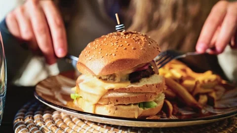 Gourmet burger served on a patterned plate in bright daylight, with blurred Stock Footage 323012691