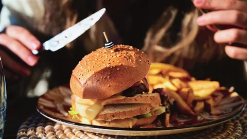Gourmet burger served on a patterned plate in bright daylight, with blurred Stock Footage 323012829