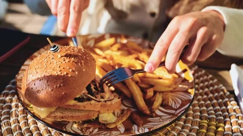 Gourmet burger served on a patterned plate in bright daylight, with blurred Stock Footage 323015167