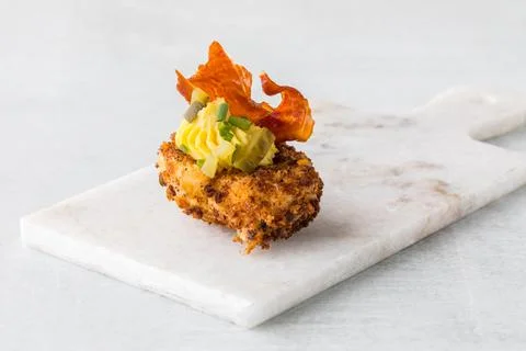 A gourmet deep fried deviled egg garnished with fried prosciutto and chives. Stock Photos