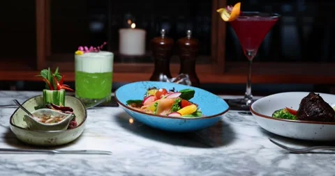 Gourmet dining setup on marble table with colorful dish and cocktails, Видео 318118126