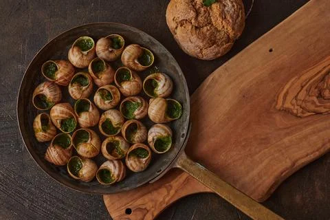 Gourmet dish featuring escargot in a rustic pan, garnished with herb butter.. Stock Photos