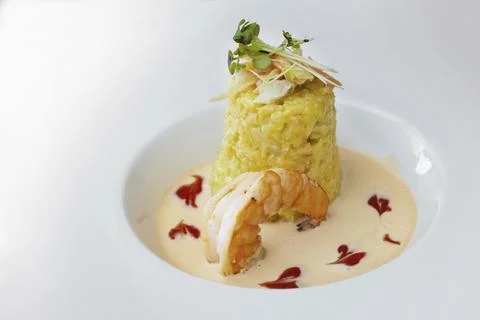 Gourmet dish from saffron risotto with vegetable and herb topping, a large prawn Stock Photos