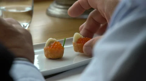 Gourmet eats tiny canapes with red caviar in the restaurant. Stock Footage 63820950