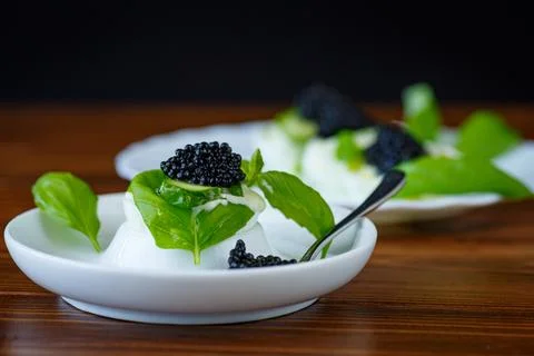 Gourmet egg with black caviar on rustic wooden background Stock Photos