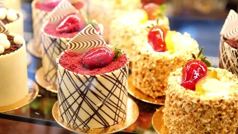 Gourmet pastry selection in shop window display showing delicious small cak.. Stock Footage 332858595