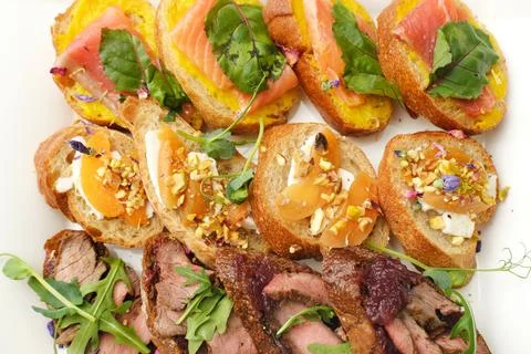 Gourmet platter featuring assorted canapes with smoked salmon, savory meats, and Stock Photos