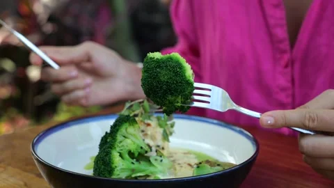 Gourmet pricked broccoli on fork close-up. Cinematic video of young woman eating Stock Footage 255303442