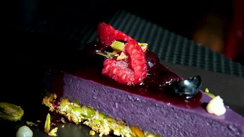 Gourmet raspberry dessert - Enjoying a Slice of Purple Berry Cake Topped with Stock Footage 314092201