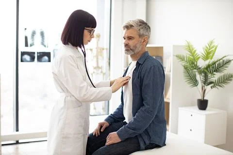 GP using stethoscope during patient's checkup in exam room 스톡 사진