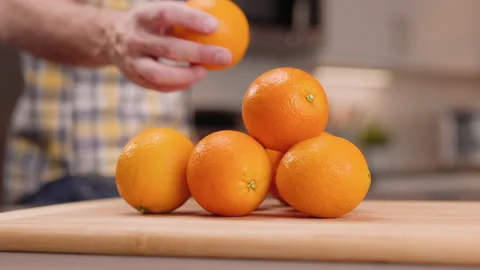 Grab an Orange from a Stack and Inspects to Eat Stock Footage 155112561