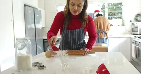 Grabbing red measuring cup, Hispanic woman scooping flour and rolling dough for Stock Footage 342392134