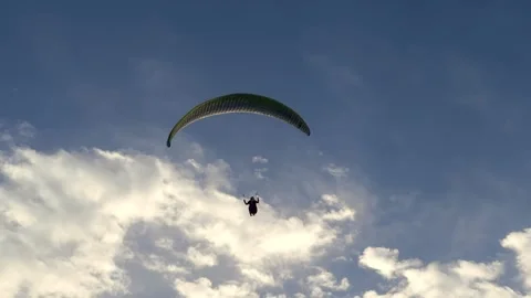 With grace, a paraglider pilot ascends amidst the azure sky, epitomizing Stock Footage 274344282