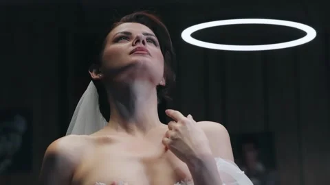 Graceful angel bride looking up with illuminated halo emphasizing serenity an Stock Footage 344703232