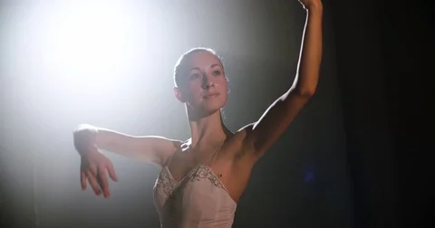 A graceful ballerina dancing ballet elements in the dark with light and smoke on Stock Footage 73423517