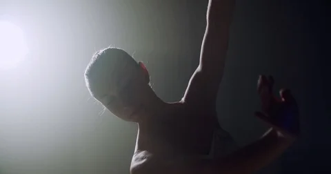 A graceful ballerina dancing ballet elements in the dark with light and smoke on Stock-Footage 73936074