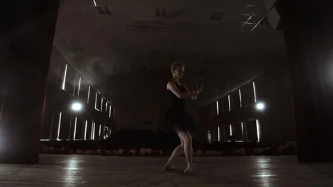 A graceful ballerina dancing ballet elements in the dark with light and smoke on Stock Footage 112867911