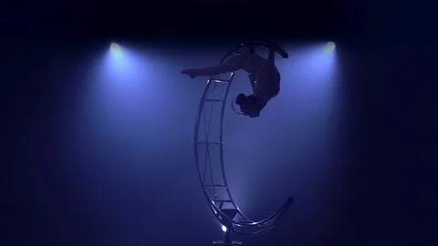 Graceful in a brilliant costume performs tricks on a special design in a dark Stock Footage 99500539