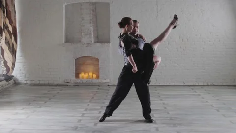 Graceful couple dances hot tango near decorative fireplace Stock Footage 136428486