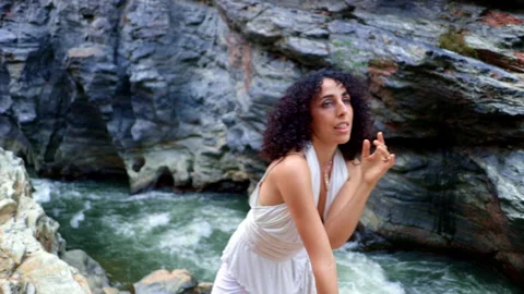 A Graceful Dancer Expresses Emotion and Movement by a Cascading River Amidst Stock Footage 314197496