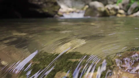 The graceful entry of the hand into the flowing stream water.  Stock Footage 212440100