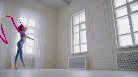 Graceful gymnast jumps high on split with bright gymnastic ribbon. Concept of Stock Footage 145047617