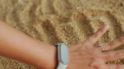 Graceful hand movements forming patterns in sunlit sand. Peaceful gestures Stock Footage 335410414