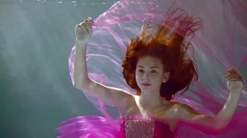 Graceful slender young girl model posing underwater in the sun dressed in Stock Footage