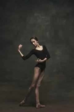 Graceful young ballet dancer isolated on dark background. Art, motion, action Stock Photos