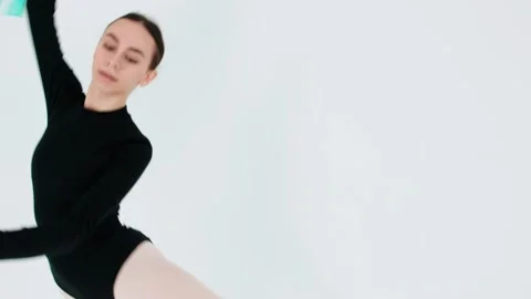 A graceful young girl performs a classical ballet dance in a white studio with a Stock-Footage 197612488