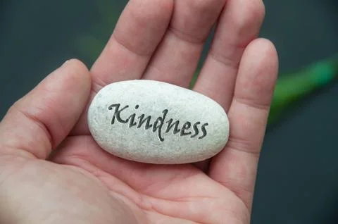 Graciousness text engraved on the stone hold by han Stock Photos