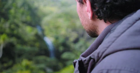 Graded C4K 120fps Man looking at waterfall Stock Footage 136542309