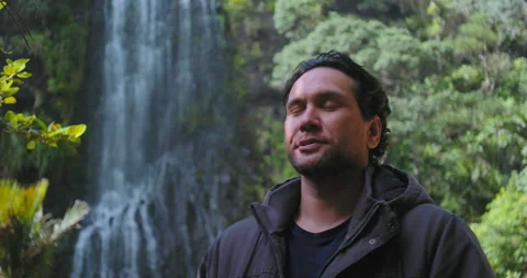 Graded C4K 120fps Man at waterfall breathes in deep looking peaceful Stock Footage 136548426