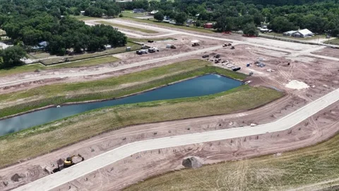 Graded dirt roads wind between retention ponds at housing development site in Stock Footage 340856990