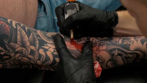 Tilt up of tattoo artist spraying and placing tattoo stencil on mans arm -  Slow Motion | ClipStock