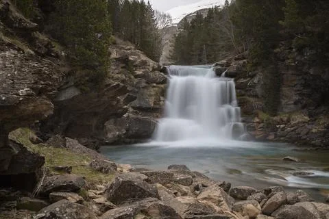 Graded waterfall flowing into blue river in pyrenees mountains Stock Photos
