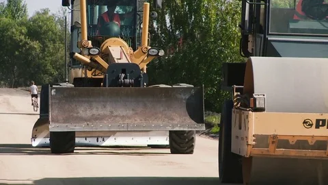 The grader and the road roller move along the road under construction Video stock 81240803