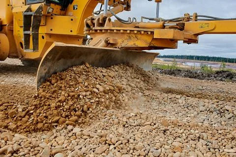 The grader blade levels the rubble at the construction site Stock Photos