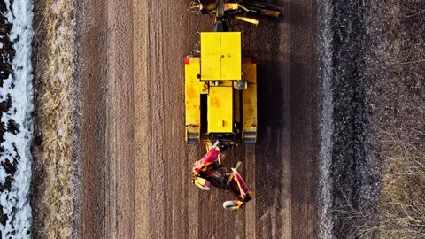 Grader machine leveling gravel surface for road maintenance and repair in Stock Footage 334120264