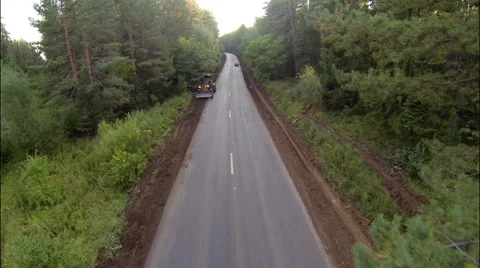 Grader on the road in the woods, aerial view Stock Footage