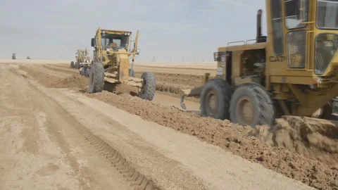 Graders level the road in the desert, preparing for the construction of roads Stock Footage 145557504