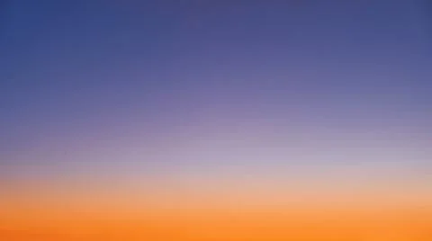 Gradient of orange-blue evening sky without clouds at sunset Stock Photos