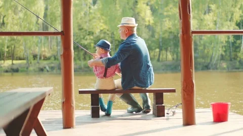Gradpa is teaching his grandson to angle on fishing at the lake Stock Footage 78373145