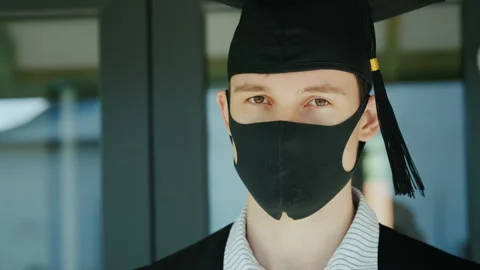 Graduate in a protective mask and cap, graduating from college under quarantine Stock Footage 134375654