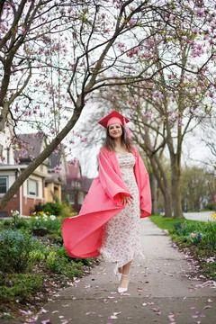 Graduating student walks on path surrounded by flowers in spring season cel.. 库存照片