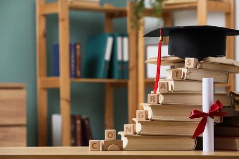 Graduation cap and diploma on a stack of books with wooden blocks spelling co 스톡 사진